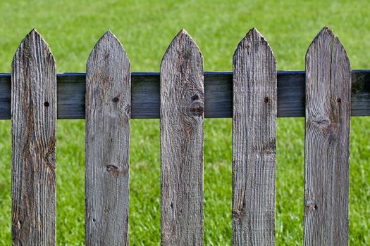 Weathered wood picket fence against the grass