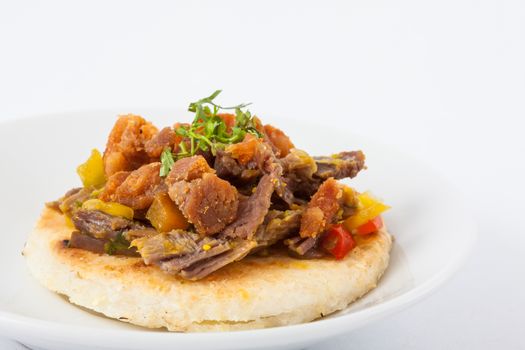 Colombian arepa topped with shredded beef and pork rind