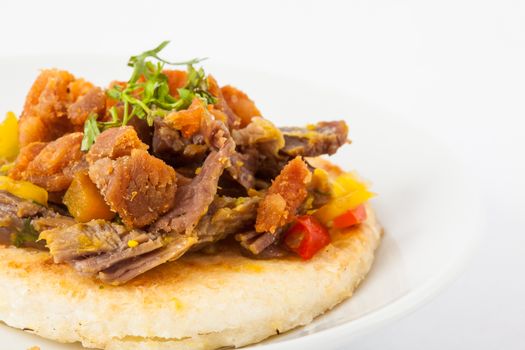 Colombian arepa topped with shredded beef and pork rind