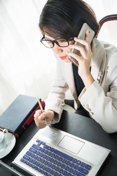 Young asian woman short hair in smart casual wear working on laptop while sitting near window in home office