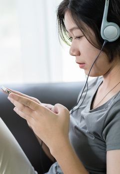 Close up young asian woman short hair listening music from mobile phone on the couch