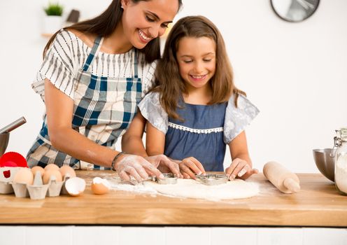 Shot of a mother and daughter having fun in the kitchen and learning to make a cake