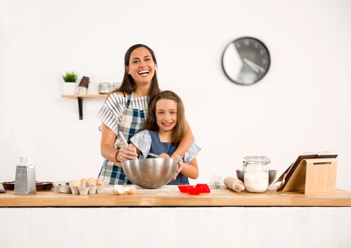 Shot of a mother and daughter having fun in the kitchen and learning to make a cake