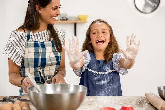 Shot of a mother and daughter having fun in the kitchen and learning to make a cake