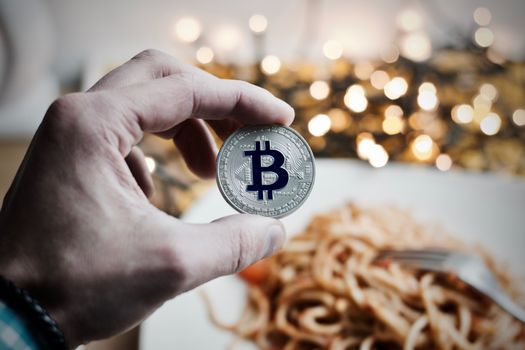 Digital currency physical metal bitcoin coin. Restaurant pasta concept.