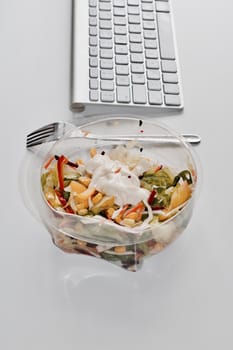 Eat near computer keyboard. Delicious fresh salad with mayo.