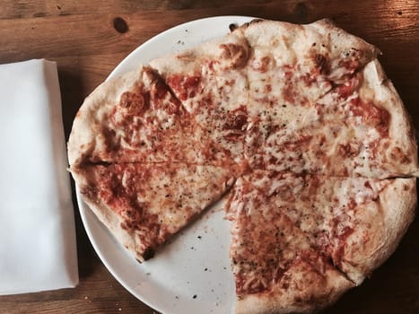 Fresh and tasty italian pizza slices on white plate in restaurant.