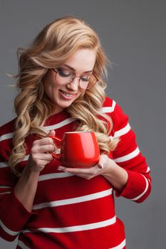 Beautiful woman in glasses holding red cup, studio shot