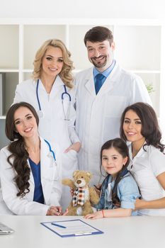 Young mother with daughter and droup of doctors in clinical office