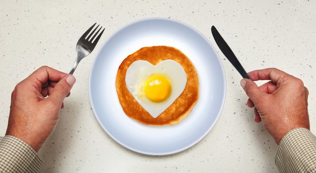 tableware in hands of man and scrambled egg on plate