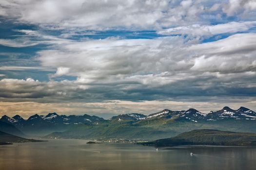 Cloudscape over the mountains in Molde with some boats in the fjord, Norway