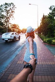 Beauty woman in blue hat holding man by hand and going around the Alanya city in Turkey