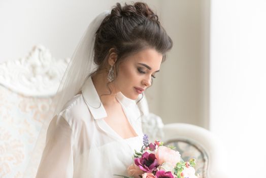 Beautiful bride posing in her wedding day with flower bouquet