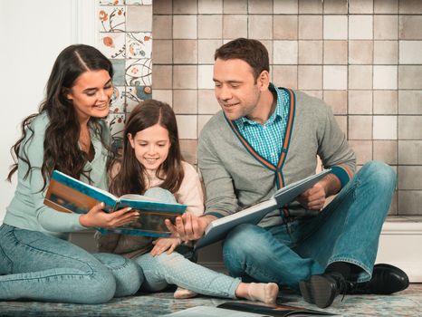 Family portrait of happy parents and their daughter read together at home