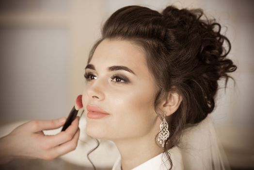 Artist applying blush to wedding make up for bride