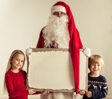 Santa Claus with children holding vintage paper billboard with copy space for text