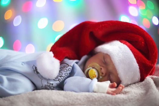 Newborn baby in santa hat on bokeh lights background