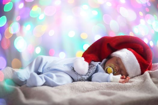 Newborn baby in santa hat on bokeh lights background