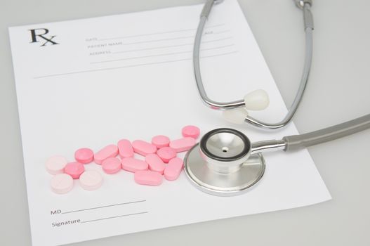 Close up old silver medical stethoscope and pink pills place on blur rx prescription form as background with white table and copy space. Healthcare and medical concept photography.