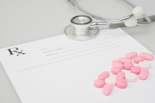 Close up pink pills on blur rx prescription form with old silver medical stethoscope on white background and copy space. Healthcare and medical concept photography.