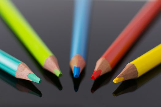 Multicolor pencils forming a semicircle with reflection on black plexiglass
