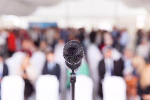 Participants at the business or professional conference. Microphone in focus against blurred audience.