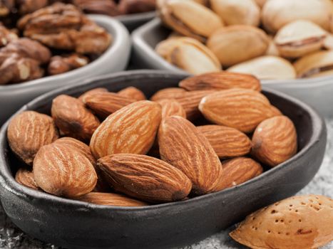 Almond in trendy plate close up on gray cement background.