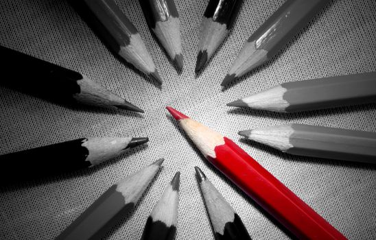 Red pencil standing out in a group of black and white pencils