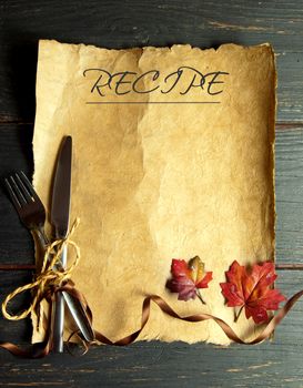 Recipe on paper scroll with fork and knife tied with ribbon bow and autumn leaves