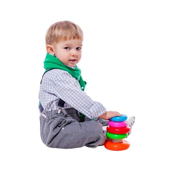 Toddler boy playing with colorful pyramid toy isolated on white