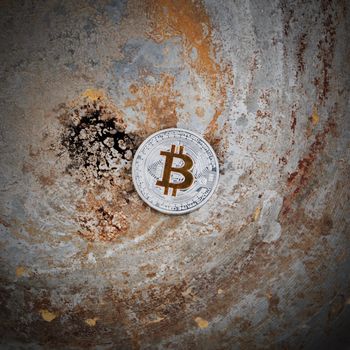 Crypto currency physical metal silver bitcoin coin on dirty scene.