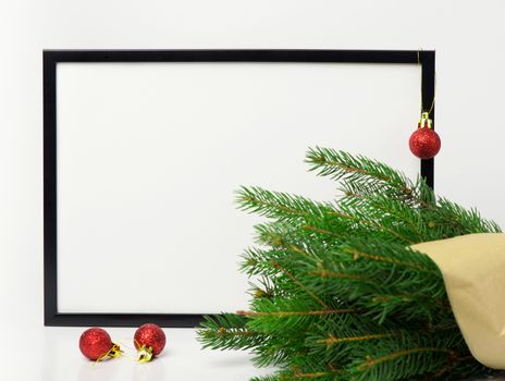 Christmas composition. Black frame and  branches christmas tree, red balls on white background. Front view, mock up, copy space, square, flat lay, for congratulations

