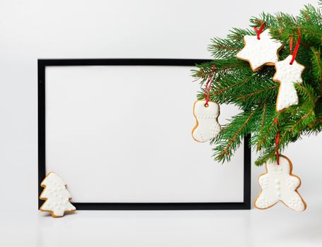 Christmas composition. Black frame and  branches christmas tree with gingerbreads on white background. Front view, mock up, copy space, square, flat lay, for congratulations

