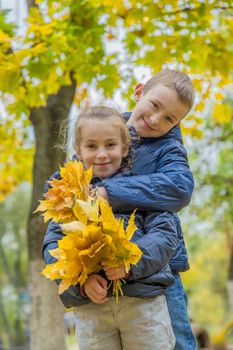 Sister and brother hugging among autumn forest