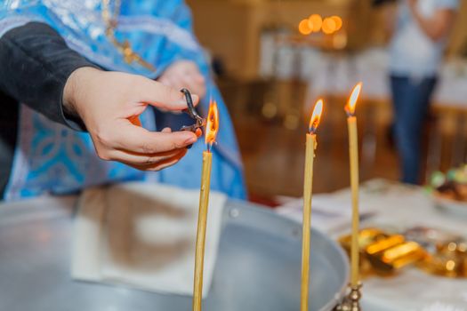 Priest burning hair in candle flame in orthodox church