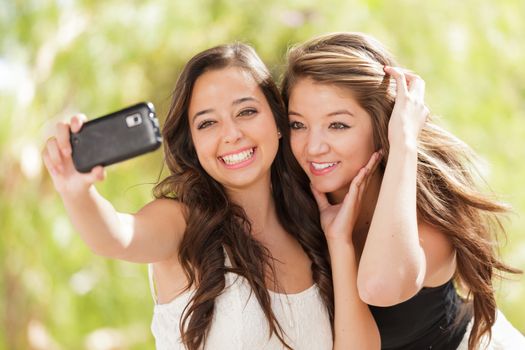 Two Attractive Mixed Race Girlfriends Using Their Smart Cell Phones For Selfie Outdoors