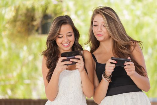Two Expressive Mixed Race Girlfriends Using Their Smart Cell Phones Outdoors