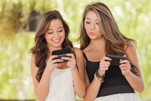 Two Expressive Mixed Race Girlfriends Using Their Smart Cell Phones Outdoors