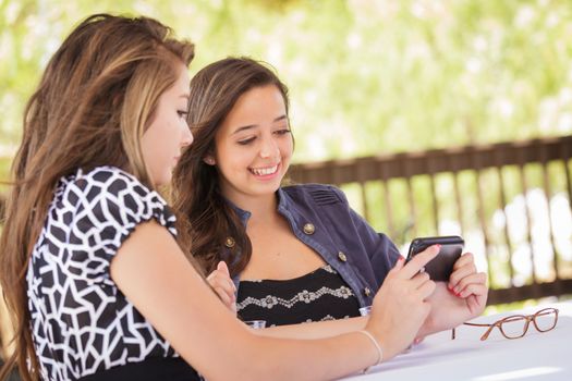 Expressive Young Adult Girlfriends Using Their Smart Cell Phone Outdoors