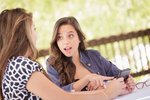 Expressive Young Adult Girlfriends Using Their Smart Cell Phone Outdoors