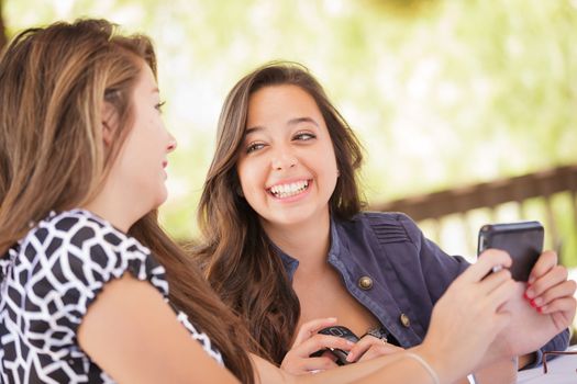 Expressive Young Adult Girlfriends Using Their Smart Cell Phone Outdoors