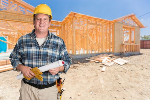 Male Contractor With House Plans Wearing Hard Hat In Front of New House Construction Framing