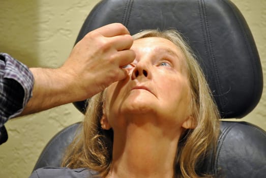 Mature female blond beauty having an eye exam inside a clinic.