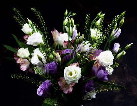 Elegant Flowers Bouquet with White and Purple Lisianthus, Alstroemeria and Decorative Green Stems closeup on Dark Grunge background