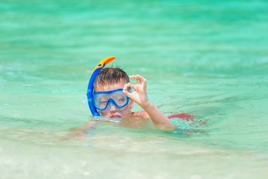 portrait of a boy in a snorkeling mask showing a gesture