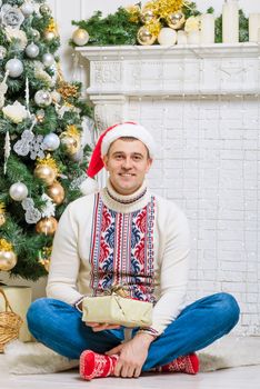 portrait of a man with a gift near a Christmas fir