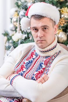 portrait of a man sitting in a chair near Christmas fir