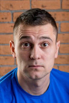 portrait of a man with surprise on his face against a brick wall background