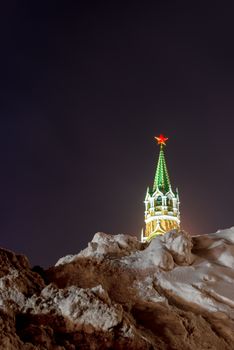 a pile of snow and a view of the Kremlin tower in Moscow on a winter evening