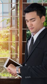 asian businessman holding tablet and looking at wrist watch